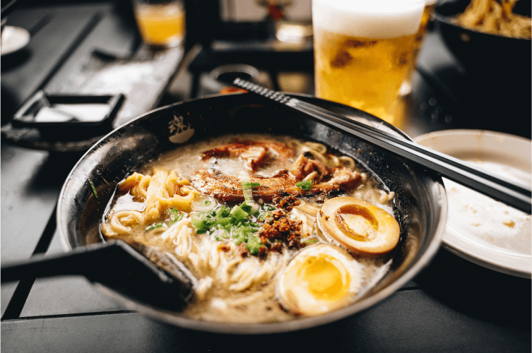 A bowl of ramen noodle soup with sliced soft-boiled eggs, green onions, and pork.