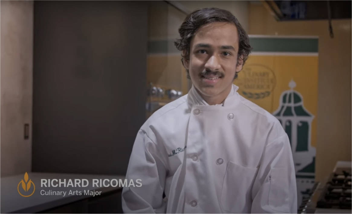 A person with a mustache is smiling and wearing a white chef's coat. The text "Richard Riconas, Culinary Arts Major" is displayed on the left side of the image. In the background, there is a banner that appears to be related to a culinary arts program.