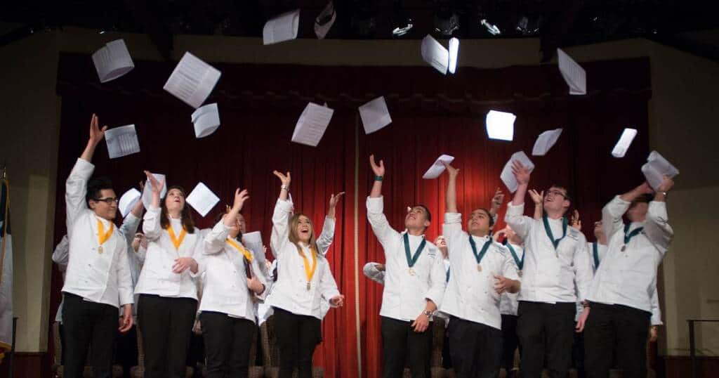 Culinary Institute of America students celebrating graduating with their culinary arts degrees.