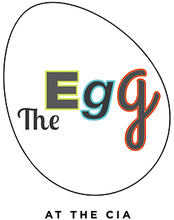 A logo featuring an outline of an egg. Inside the egg outline, text reads "The Egg" with each letter uniquely stylized. Below the egg outline, the text reads "At The Egg CIA.