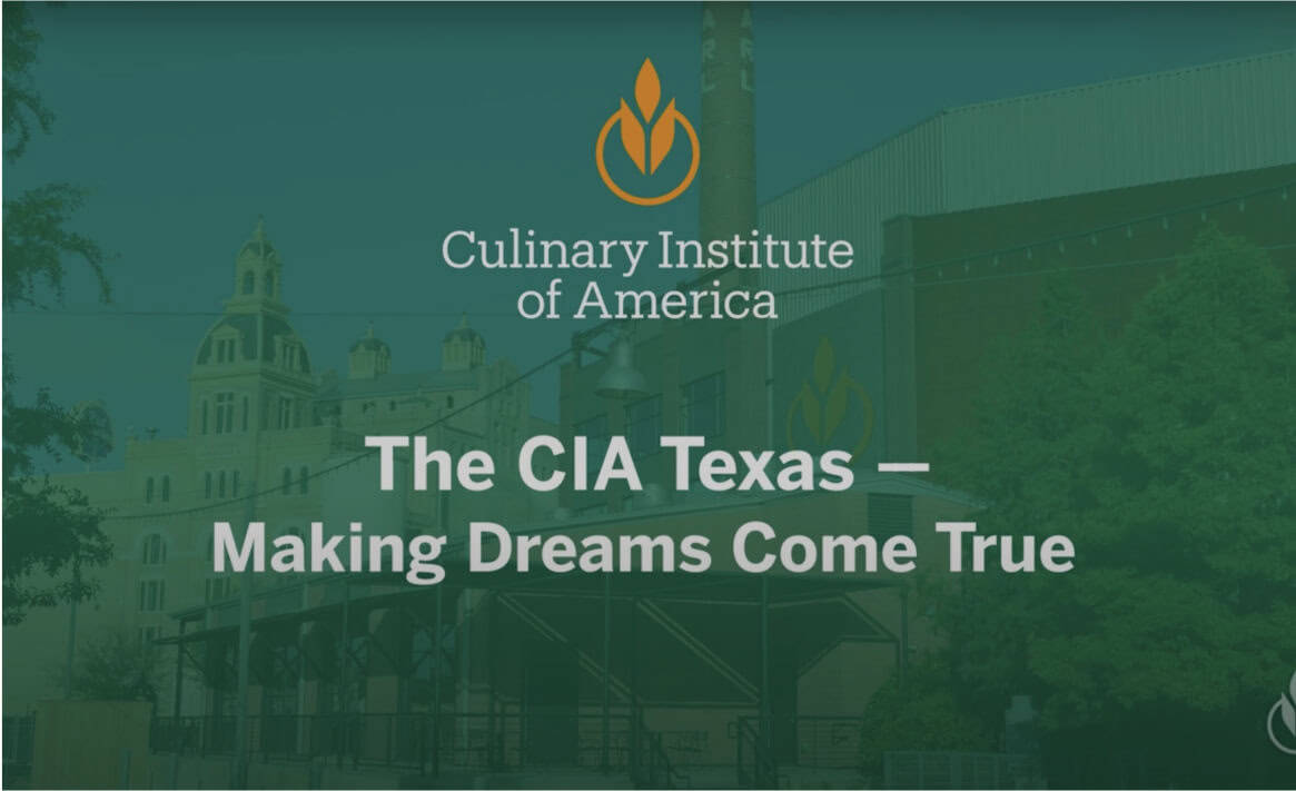 Exterior view of the Culinary Institute of America in Texas, with the logo and text "Culinary Institute of America - The CIA Texas - Making Dreams Come True" displayed prominently. Buildings and trees are in the background.