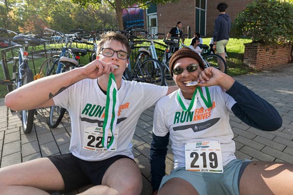 Two runners biting their medals from the 13th annual Run for Your Knives 5K held during Alumni Weekend on the Hyde Park, NY campus.